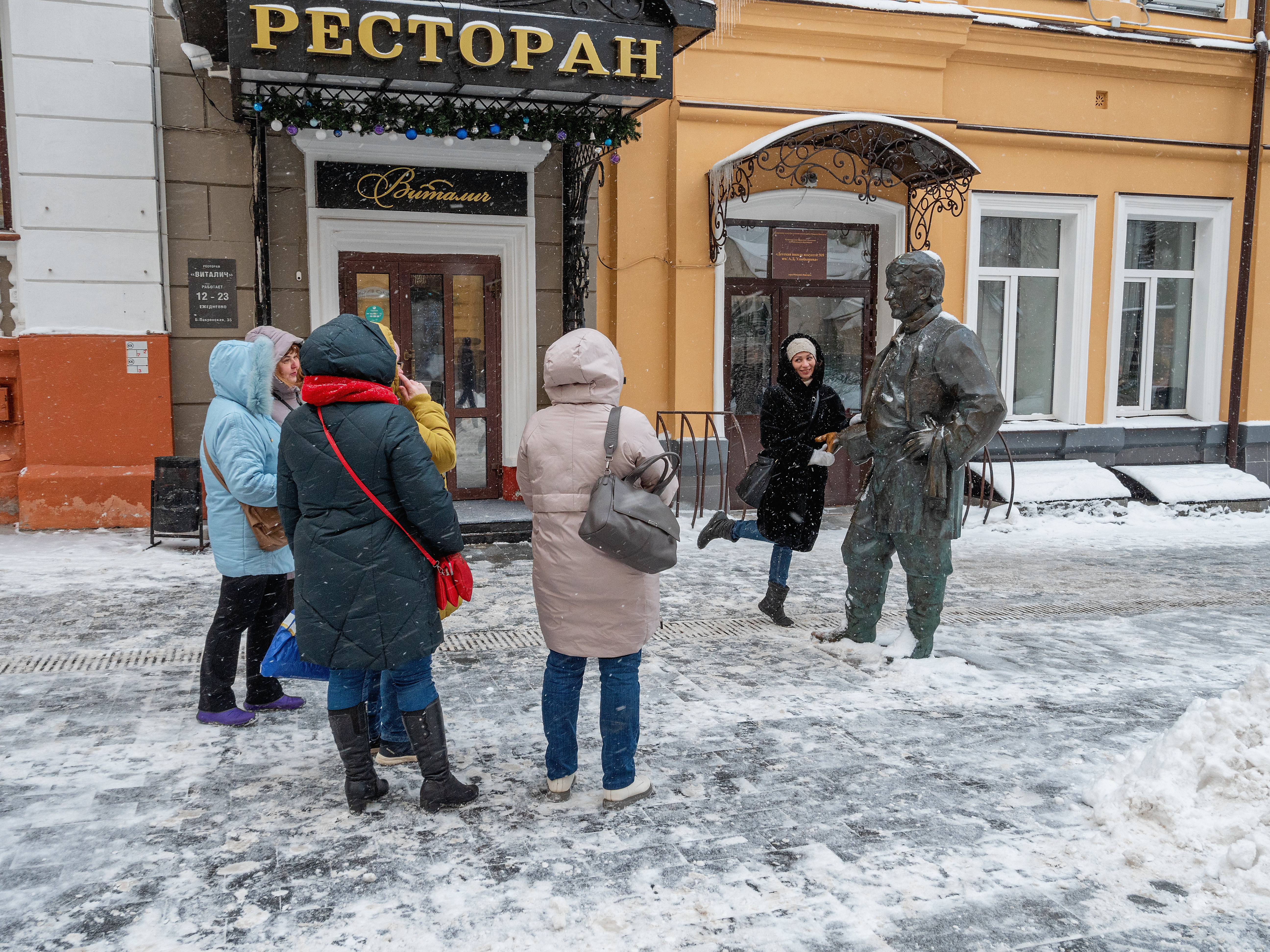 Нижний Новгород. Улица Большая Покровская зимой. Туристы фотографируются у скульптуры официанта.