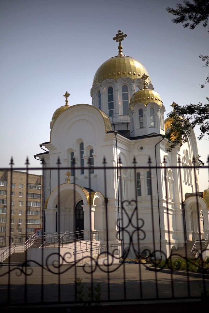 Храм с золотыми куполами за железной изгородью