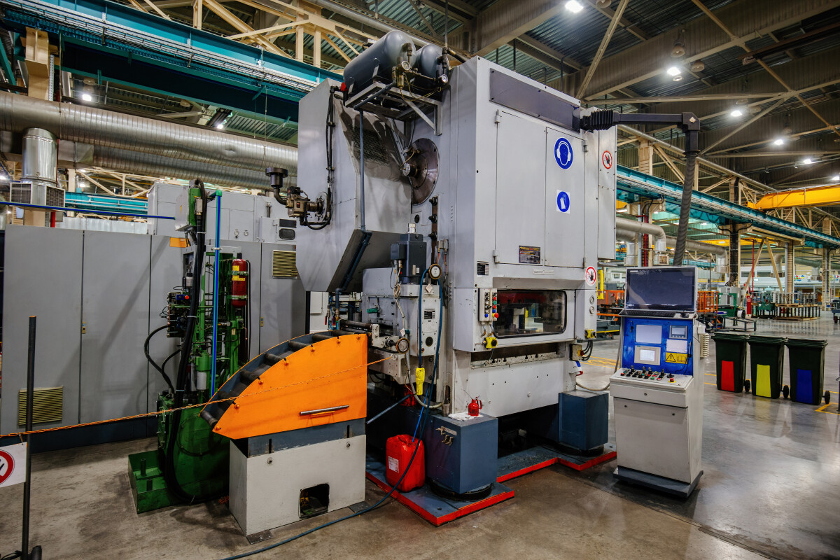 Stamping press and conveyor at metalworking factory workshop.