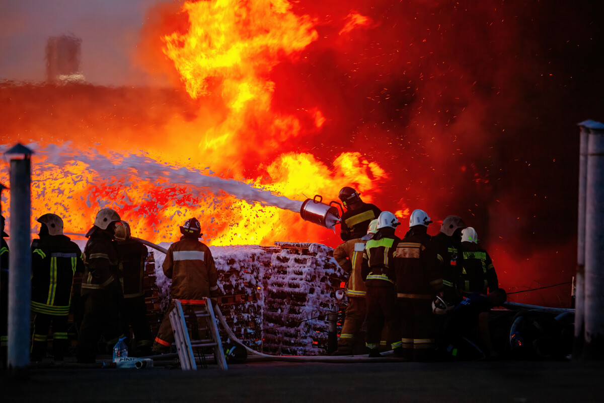 Firefighters extinguish burning industrial building with foam