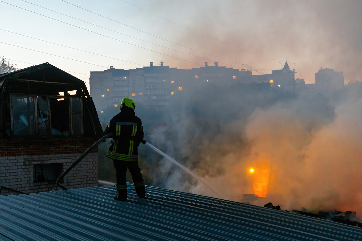 Firefighter extinguish fire in house using spraying hose