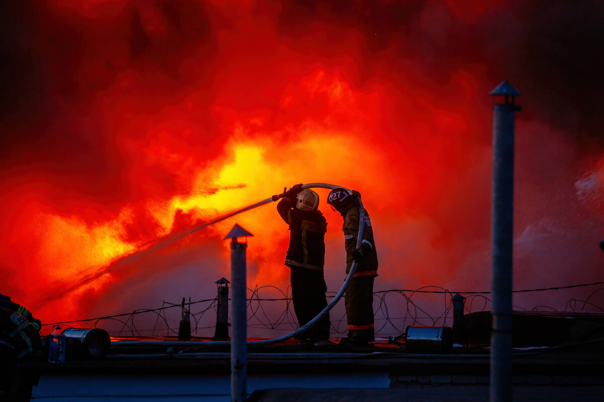 Firefighters extinguishing burning building on the roof