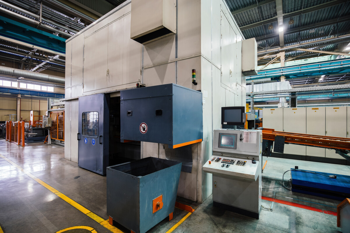 Stamping press and conveyor at metalworking factory workshop.