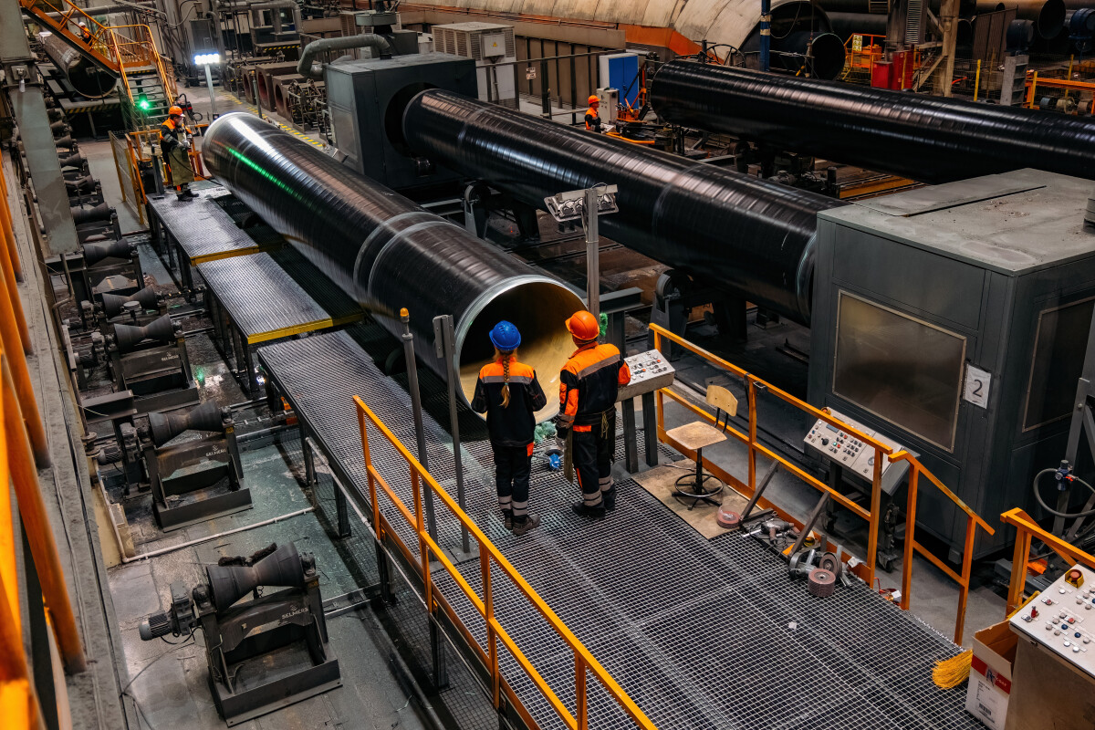 Engineers inspecting large manufactured steel pipes