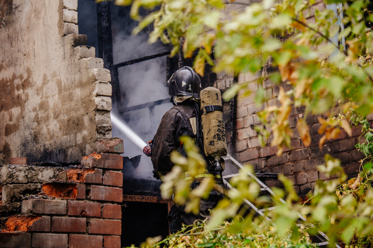 Firefighter extinguish fire in house using spraying hose