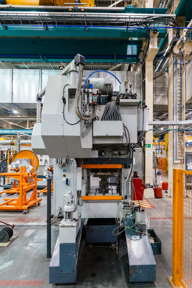 Stamping press and conveyor at metalworking factory workshop.