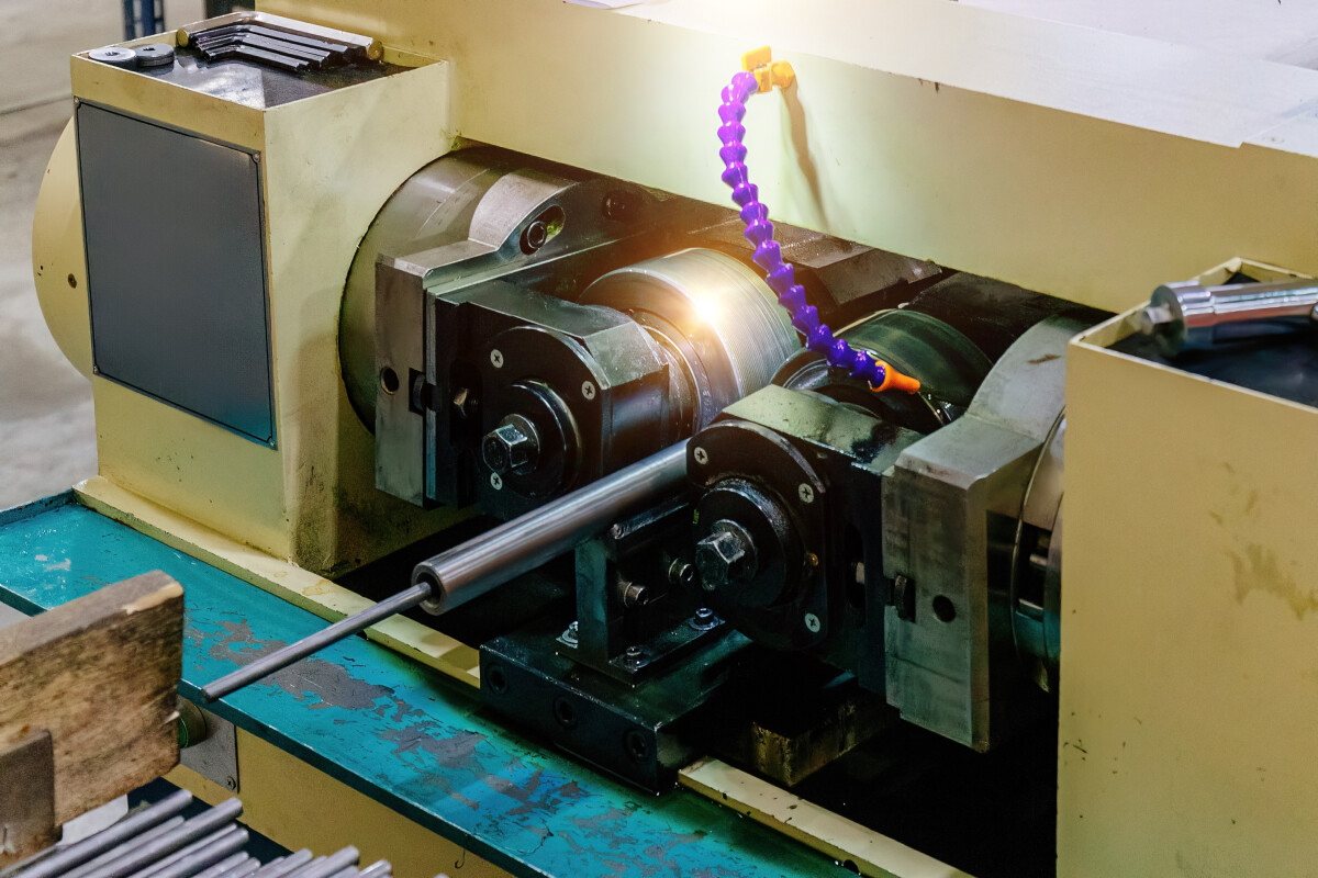 Lathe machine tapping steel rods, close up