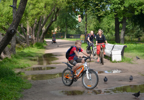 САНКТ-ПЕТЕРБУРГ, РОССИЯ - 24 июля 2015 года: Семья на велосипедах едет по дорожке парка