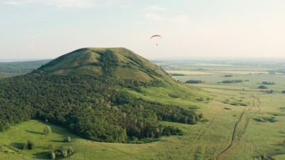 Южный Урал, мотопараплан пролетает над горой Торатау. Вид с воздуха.