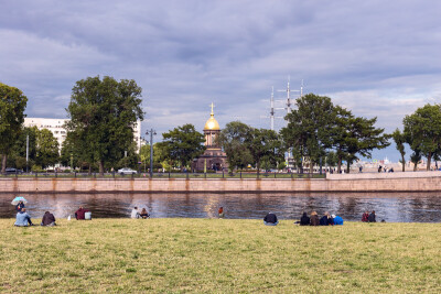 Санкт-Петербург, Россия - 13 июля 2019 г. - группа молодых людей отдыхает на берегу Невы